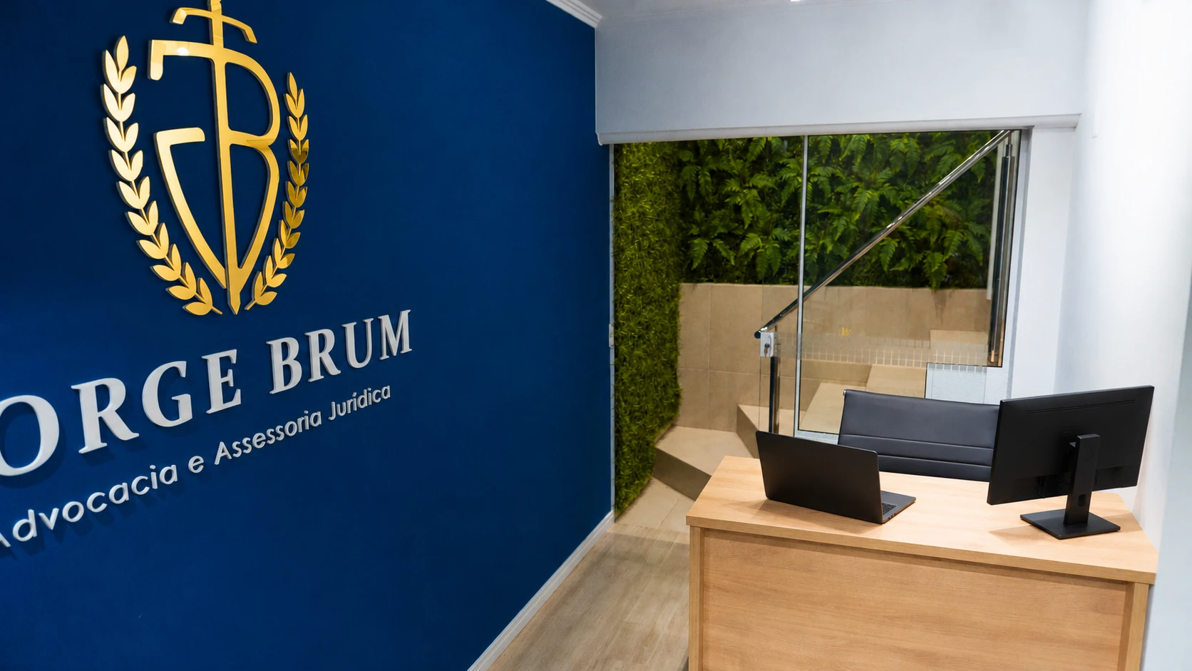Recepção da Jorge Brum Advocacia, com notebook preto e monitor sobre a mesa